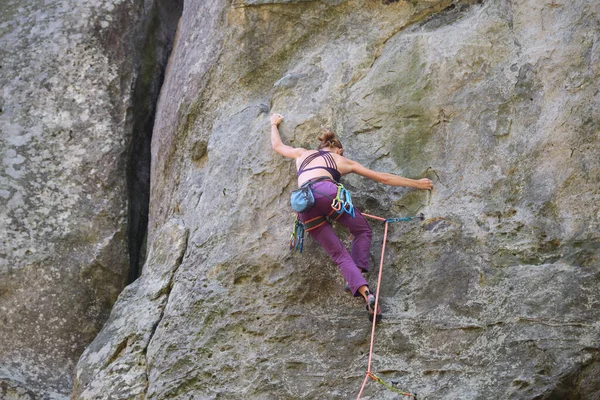 強い女性登山岩の山の急な壁を登る。難しいルートを克服するスポーツ女性。極端なスポーツ趣味の概念に従事 — ストック写真