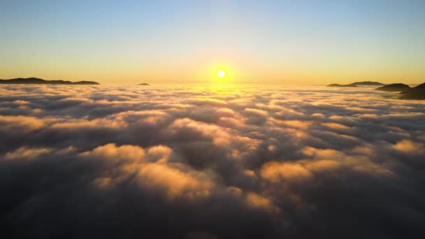 Luchtfoto van kleurrijke zonsopgang boven witte dichte mist met verre donkere silhouetten van berghellingen aan de horizon — Stockvideo