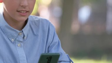 Yazlık parkta cep telefonuyla konuşan mutlu genç çocuk.