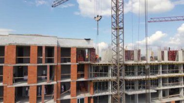 İnşaat halindeki yüksek beton binadaki vinçler ve profesyonel işçiler. Gayrimenkul geliştirme kavramı