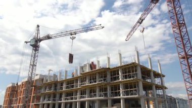 İnşaat halindeki yüksek beton binadaki vinç ve işçiler. Gayrimenkul geliştirme kavramı