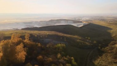Kazı makineleri ve çöp kamyonlarıyla inşaat endüstrisi için kumtaşı malzemelerinden oluşan açık maden manzarası. Madencilik ve kullanışlı mineral üretiminde ağır ekipman