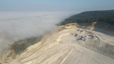 Kazı araçları ve çöp kamyonları ile inşaat endüstrisi için kireçtaşı malzemelerinin açık çukur madenciliğinin hava görüntüsü