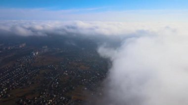 Fırtınadan önce, şişkin kümülüs bulutlarıyla kaplı uzak şehrin yüksek irtifasından gelen hava manzarası. Bulutlu havada uçak manzarası
