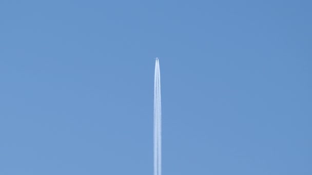 Afstand passagiersvliegtuig vliegen op grote hoogte op heldere blauwe lucht laat witte rook spoor van contrail achter. Luchtvervoersconcept — Stockvideo