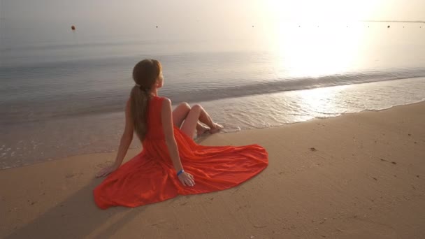 Jeune femme seule assise sur la plage de sable de l'océan au bord de la mer profitant d'une chaude soirée tropicale — Video