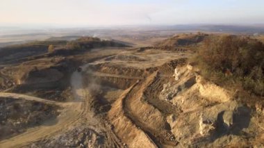 Kazı makineleri ve çöp kamyonlarıyla inşaat endüstrisi için kumtaşı malzemelerinden oluşan açık maden manzarası. Madencilik ve kullanışlı mineral üretiminde ağır ekipman