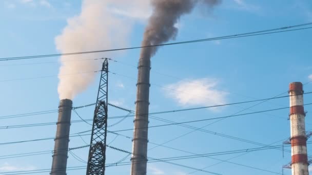 Hochspannungsmasten gegen Kohlekraftwerk hohe Rohre mit schwarzem Rauch nach oben die Atmosphäre verschmutzen. Erzeugung elektrischer Energie mit fossilem Brennstoffkonzept — Stockvideo