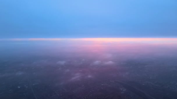 Vista aerea dal finestrino dell'aeroplano ad alta quota di terra ricoperta di bianco sottile strato di nebbia nebbiosa e nuvole lontane al tramonto — Video Stock