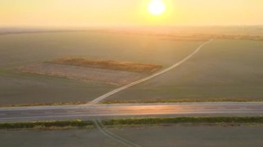 Gün batımında hızlı sürüş arabasıyla şehirlerarası yol manzarası. Akşamları otoban trafiğinin insansız hava aracı görüntüsü