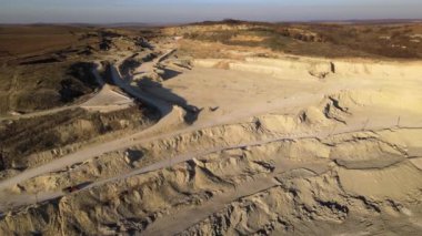 Kazı makineleri ve çöp kamyonlarıyla inşaat endüstrisi için kumtaşı malzemelerinden oluşan açık maden manzarası. Madencilik ve kullanışlı mineral üretiminde ağır ekipman