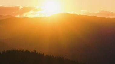 Güzel bir akşam panoramik manzarası. Gün batımında uzak dağ tepeleri üzerinde parlak batan güneş.