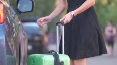 Genç bayan sürücü bagajını arabasına koyuyor. Seyahat ve tatil kavramı
