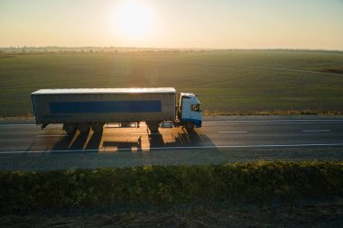 Bulanık hızlı hareket eden yarı kamyonun hava görüntüsü. Kargo karavanıyla birlikte akşamları otobanda mal taşırken görülüyor. Teslimat ulaşım ve lojistik kavramı