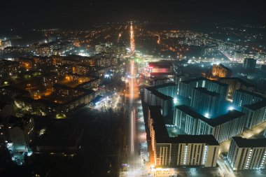Yüksek katlı apartman binalarının ve şehrin yerleşim alanındaki aydınlık sokakların havadan görüntüsü. Karanlık şehir manzarası