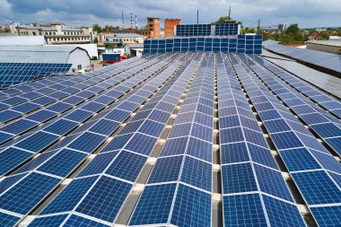 Sanayi binasının çatısına yeşil ekolojik elektrik üretmek için monte edilmiş mavi fotovoltaik panelli güneş enerjisi santralinin hava görüntüsü. Sürdürülebilir enerji konsepti üretimi