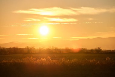 Güzel bir akşam panoramik manzarası. Gün batımında güneş batarken uzak dağ tepeleri ve asfalt yolda batıyor.