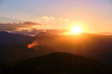 Güzel bir akşam panoramik manzarası. Gün batımında uzak dağ tepeleri üzerinde parlak batan güneş.