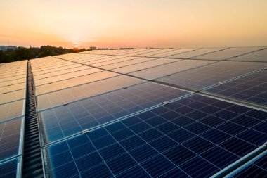 Mavi fotovoltaik güneş panelleri gün batımında temiz ekolojik elektrik üretmek için çatıya monte edildi. Yenilenebilir enerji konsepti üretimi