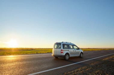 Gün batımında şehir içi yolda hızlı giden bir araba. Akşamları otoyol trafiği
