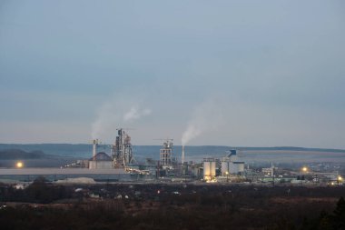 Yüksek fabrika yapısı olan çimento fabrikası ve endüstriyel üretim bölgesinde kule vinçleri var. Üretim ve küresel sanayi kavramı