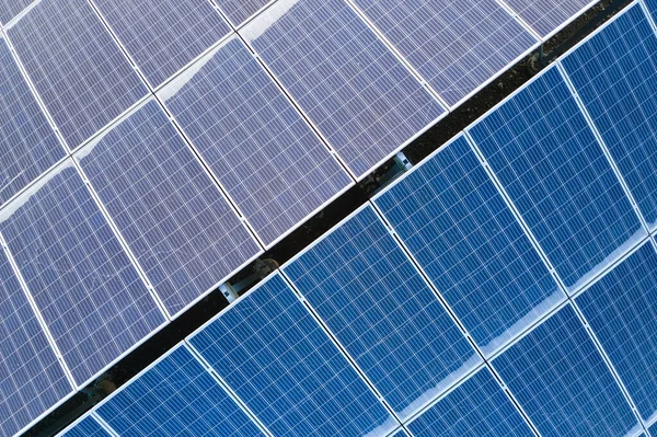 Gebouw vanuit de lucht dak met rijen blauwe fotovoltaïsche panelen voor het produceren van schone ecologische elektrische energie. Hernieuwbare elektriciteit zonder uitstoot — Stockfoto