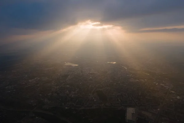 Luchtfoto van grote hoogte van verre stad bedekt met gezwollen cumulus wolken vormen voor regenbui in de avond. Vliegtuigstandpunt van bewolkt landschap — Stockfoto