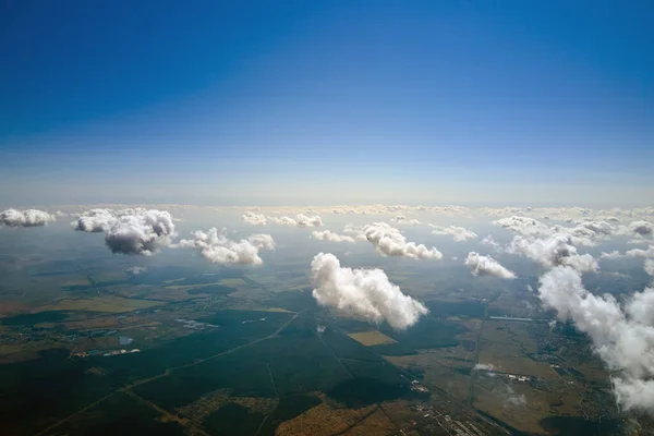 Letecký pohled z velké nadmořské výšky země pokrytý bílými nafouklými kumulativními mraky za slunečného dne — Stock fotografie