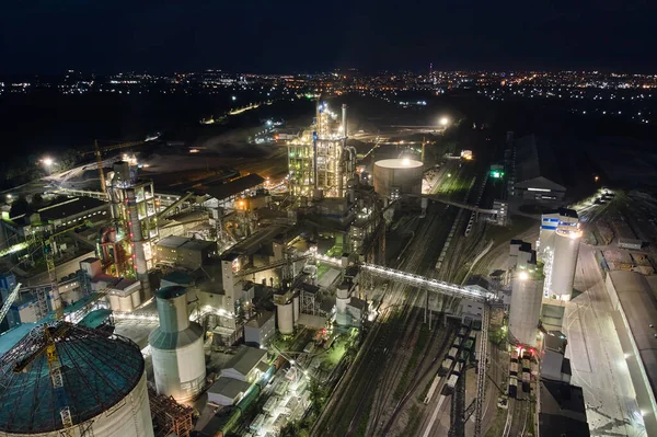 Vista aérea de la fábrica de cemento con alta estructura de planta de hormigón y grúas torre en el área de producción industrial por la noche. Fabricación y concepto de industria global — Foto de Stock