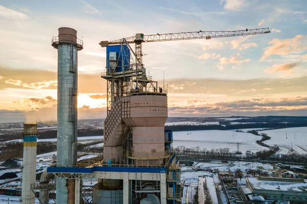 Повітряний вид на цементний завод з високою заводською структурою та баштовим краном на промисловій території на заході сонця — стокове фото