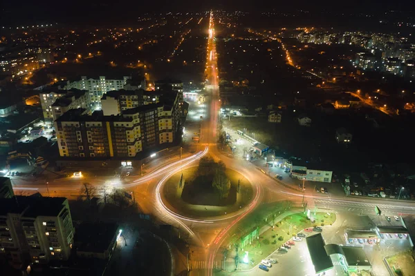 Aerial view of high rise apartment buildings and bright illuminated roundabout intersection on urban street in city residential area at night. Dark urban landscape — Stock Photo, Image