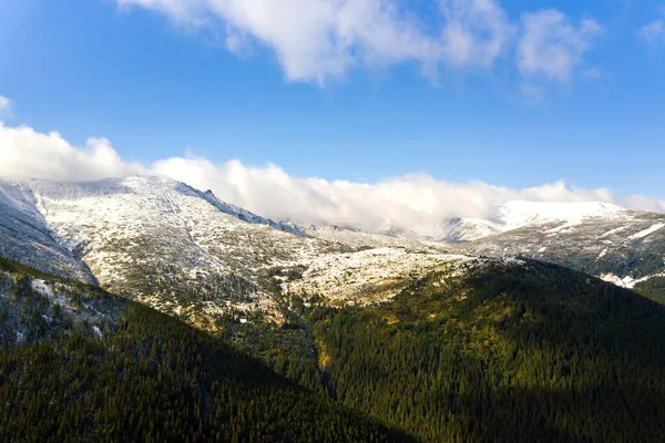 Vista aérea de majestuosas montañas cubiertas de bosque de abetos verdes y altos picos nevados — Foto de Stock