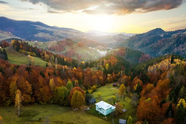 Vista aérea de pequenas casas de pastor em amplo prado entre a floresta de outono nas montanhas dos Cárpatos ucranianos ao pôr do sol — Fotografia de Stock