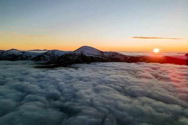 Vista aérea del vibrante amanecer sobre la densa niebla blanca con lejanas montañas oscuras de los Cárpatos en el horizonte — Foto de Stock