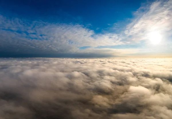 Vista aérea del vibrante amanecer amarillo sobre densas nubes blancas con cielo azul sobre la cabeza —  Fotos de Stock