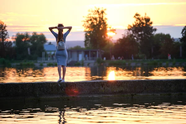 Gölün kıyısında tek başına duran ve sıcak akşamın tadını çıkaran yalnız bir genç kadın. Doğada refah ve rahatlama kavramı