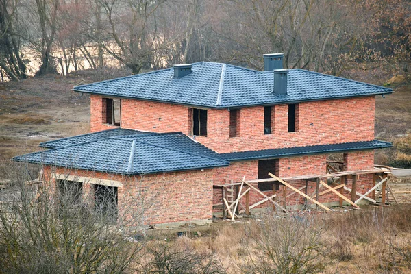 Τούβλο σπίτι με στέγη κορυφή καλύπτονται με μεταλλικό έρπητα ζωστήρα. Επικάλυψη κτιρίου υπό κατασκευή — Φωτογραφία Αρχείου