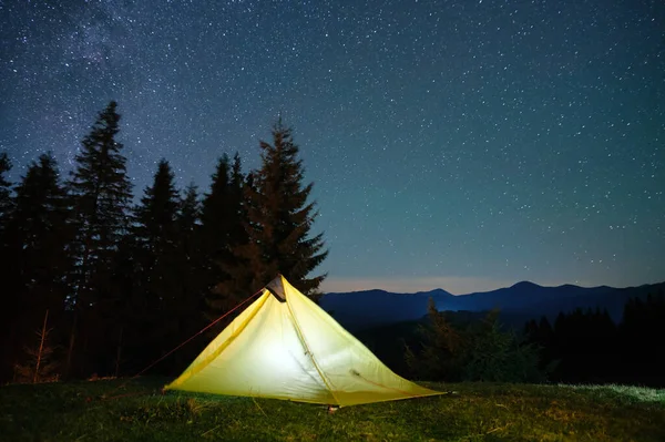 Ljus belyst camping tält glöder på campingplatsen i mörka berg under natten stjärnor täckt himmel. Aktiv livsstil och resande koncept — Stockfoto