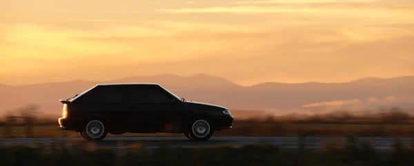 Coche que conduce rápido en la carretera interurbana al atardecer. Tráfico por carretera por la noche — Foto de Stock