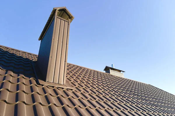 Chimney on house roof top covered with metallic shingles under construction. Tiled covering of building. Real estate development — Stockfoto