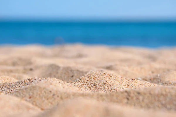 Close up de superfície de areia amarela limpa cobrindo praia à beira-mar com água do mar azul no fundo. Conceito de viagem e férias — Fotografia de Stock