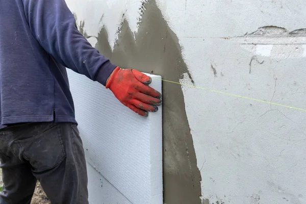 Trabajador de construcción instalando láminas de aislamiento de espuma de poliestireno en la pared de la fachada de la casa para protección térmica — Foto de Stock