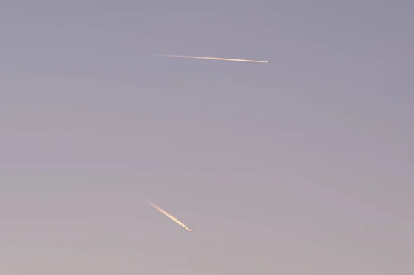 Entfernte Passagierflugzeuge fliegen in großer Höhe bei klarem blauen Himmel und hinterlassen weiße Rauchspuren von Kondensstreifen. Lufttransportkonzept — Stockfoto