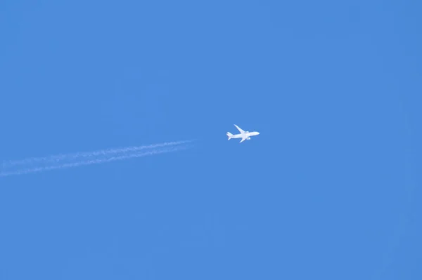 푸른 하늘높은 곳을 날고 있는 장거리 여객기는 뒤에 반사광의 흔적을 남기고 있다. 항공 수송 개념 — 스톡 사진