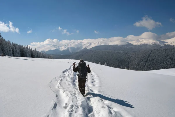 Caminante con mochila caminando en la ladera nevada de la montaña en el frío día de invierno —  Fotos de Stock