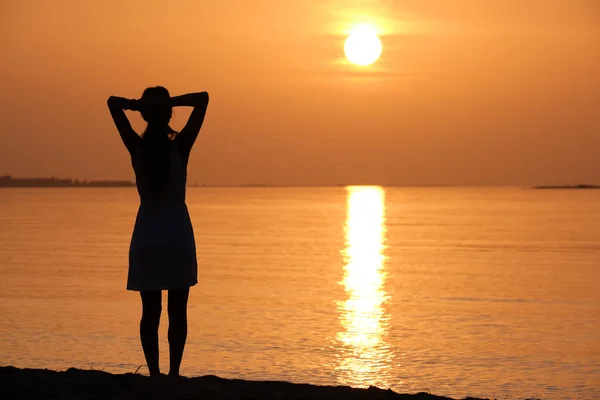 Jeune femme solitaire debout sur la plage de l'océan au bord de la mer profitant d'une chaude soirée tropicale — Photo