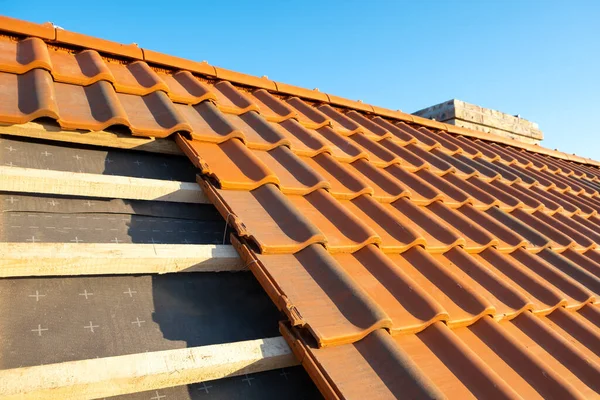 Chevauchement de rangées de tuiles de toiture en céramique jaune montées sur des planches de bois couvrant le toit du bâtiment résidentiel en construction — Photo