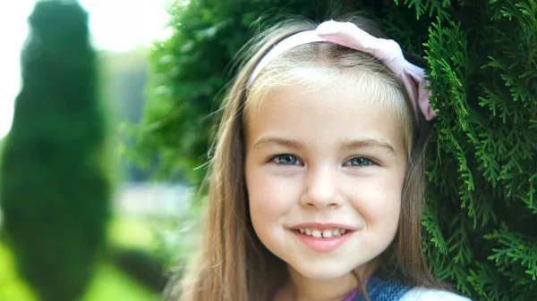 Portret van een mooi meisje dat in het zomerpark staat en vrolijk lachend in de camera kijkt — Stockfoto