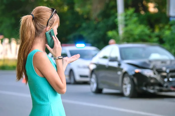 Стрессовая женщина-водитель, разговаривающая по мобильному телефону на улице, вызывает скорую помощь после автомобильной аварии. Концепция безопасности дорожного движения — стоковое фото