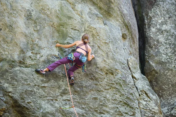 Sterke vrouwelijke klimmer klimmende steile muur van rotsachtige berg. Sportvrouw overwint moeilijke route. Betrokken bij extreme sport hobby concept — Stockfoto
